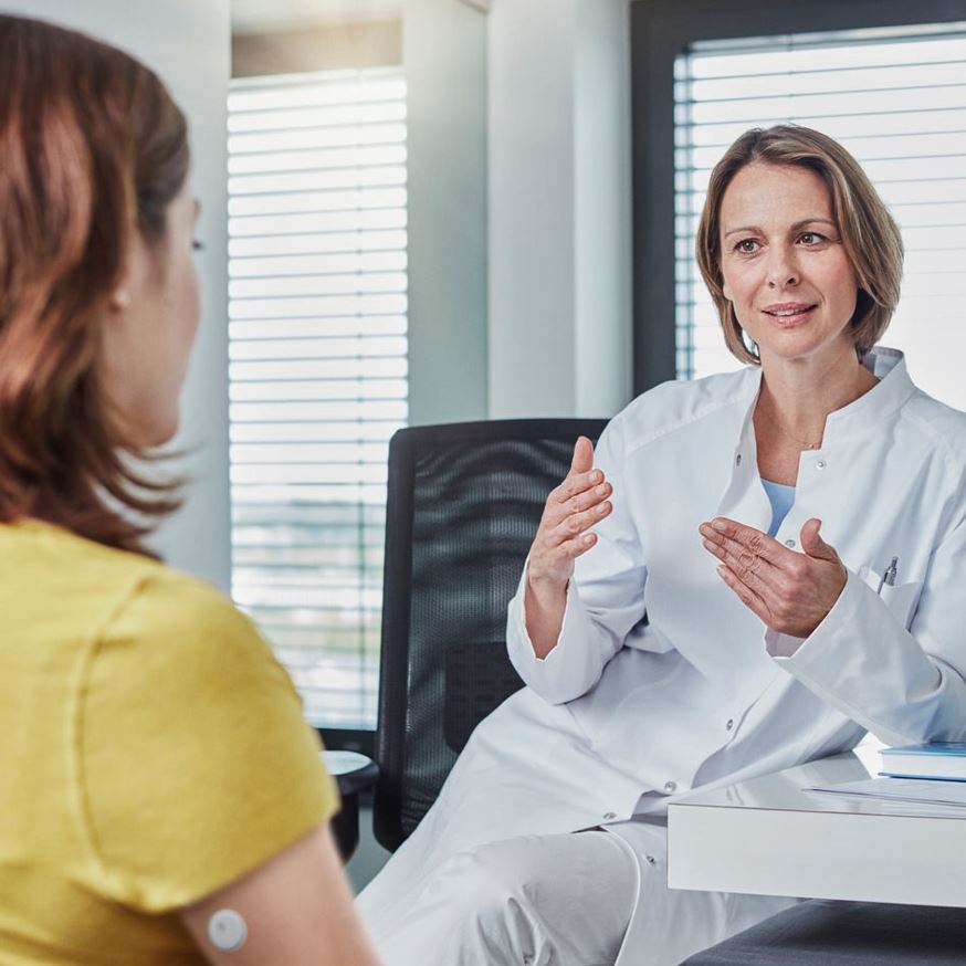 Patientin sitzt ihrer Ärztin gegenüber.
