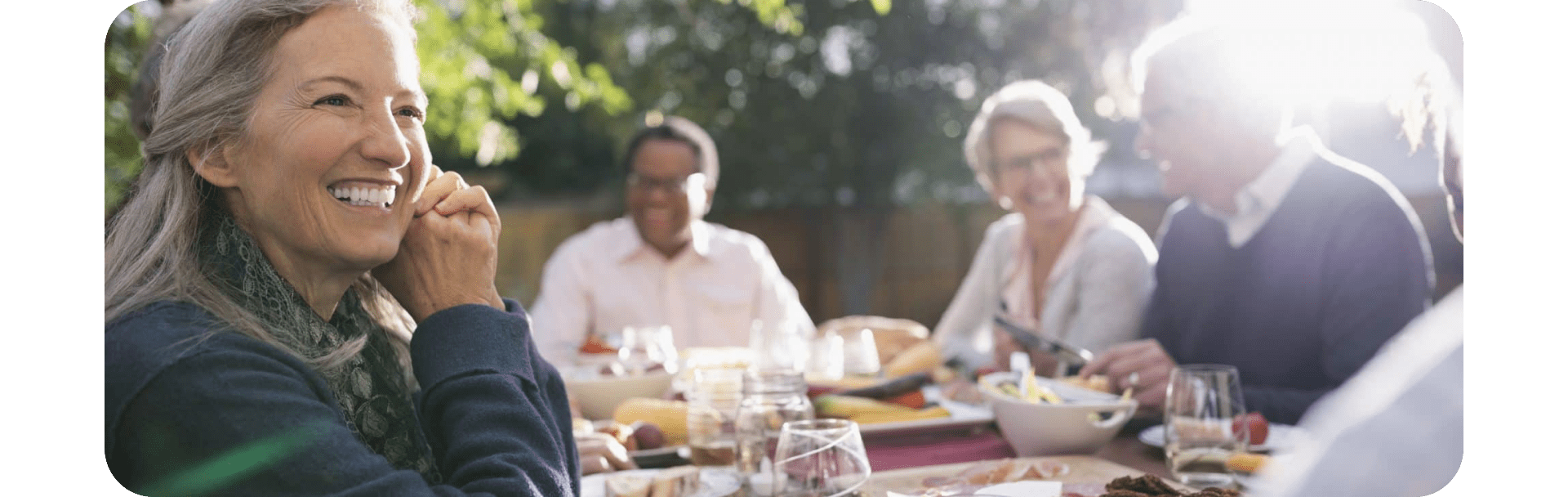 A woman eating outside and smiling.