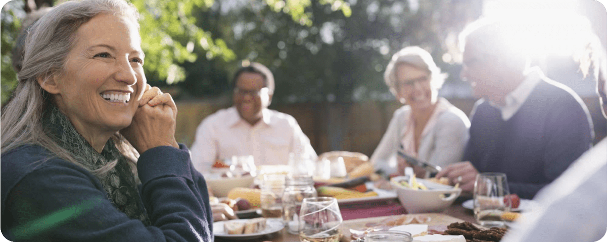 A woman eating outside and smiling.