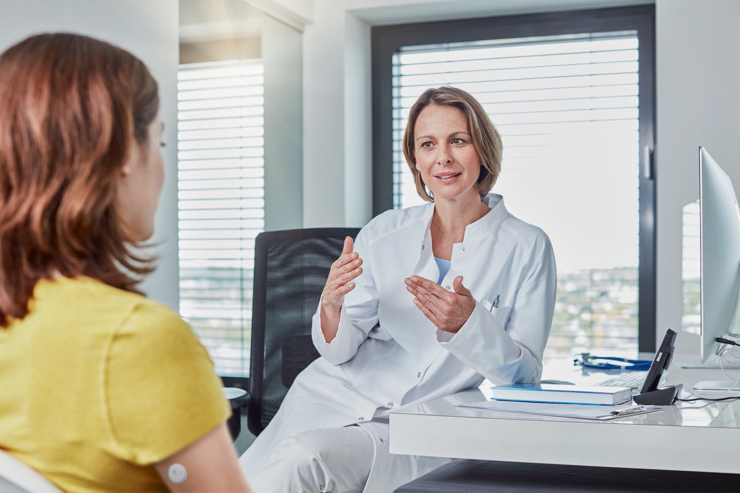 Ärztin im weißen Kittel erklärt einer Patientin etwas im Beratungsgespräch.