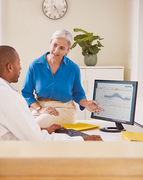 Ein Mann und eine Frau sprechen über medizinische Diagramme auf einem Computerbildschirm.