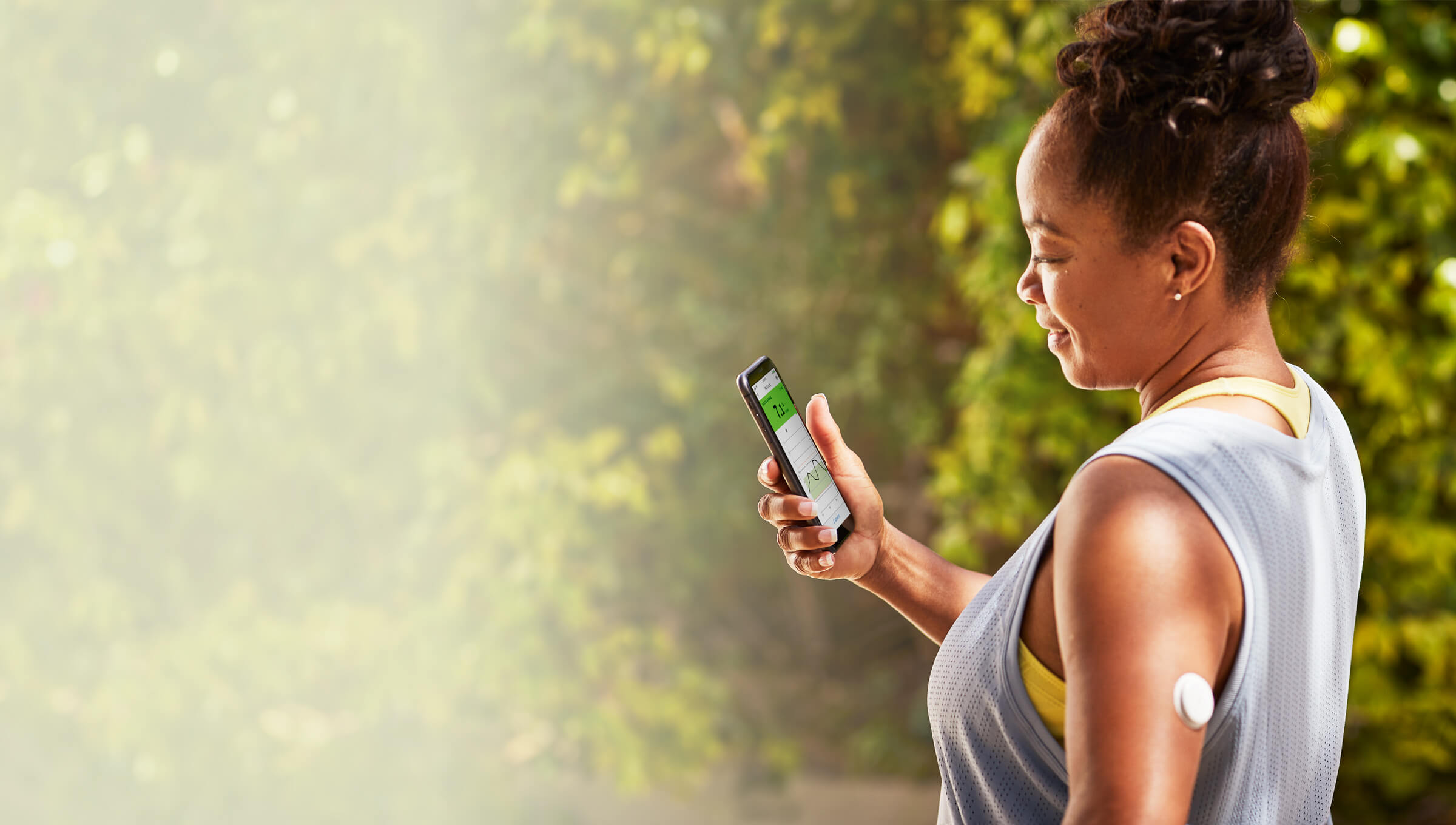 A FreeStyle Libre System user wearing sports wear with her sensor visible user smiling at her phone