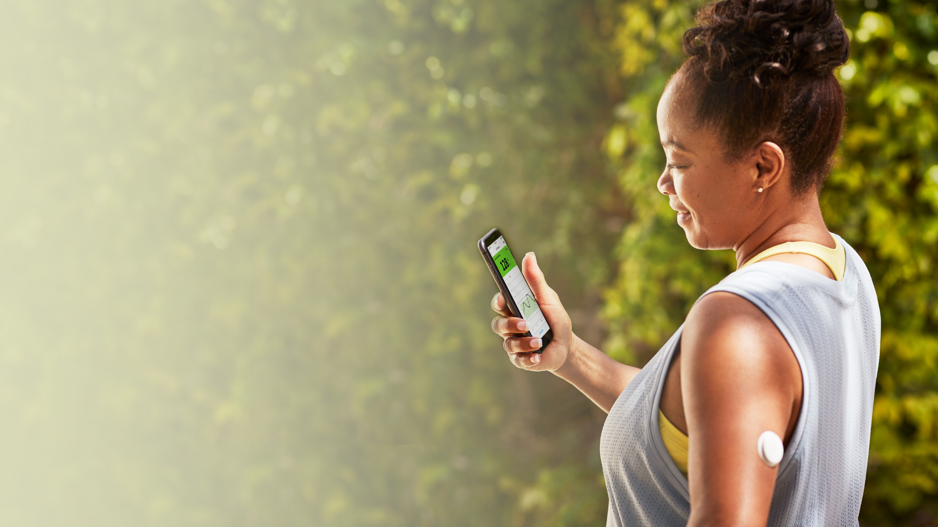 A FreeStyle Libre System user wearing sports wear with her sensor visible user smiling at her phone