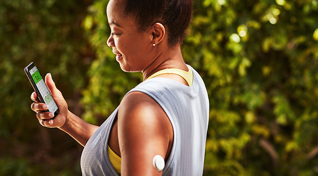 Woman on the phone checking her phone for glucose levels