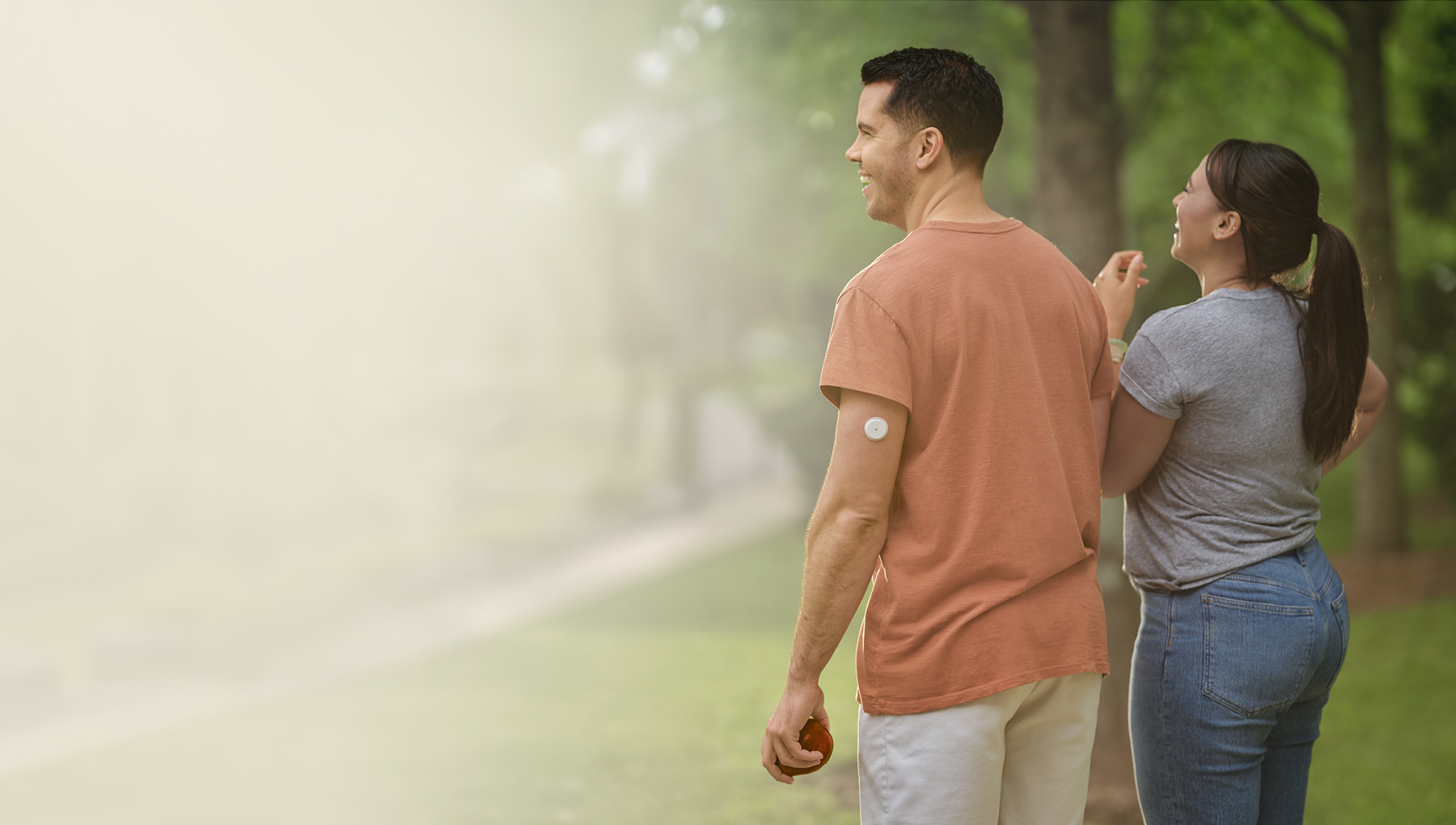 Couple walking in a park, the man is wearing a Libre 2 Plus sensor