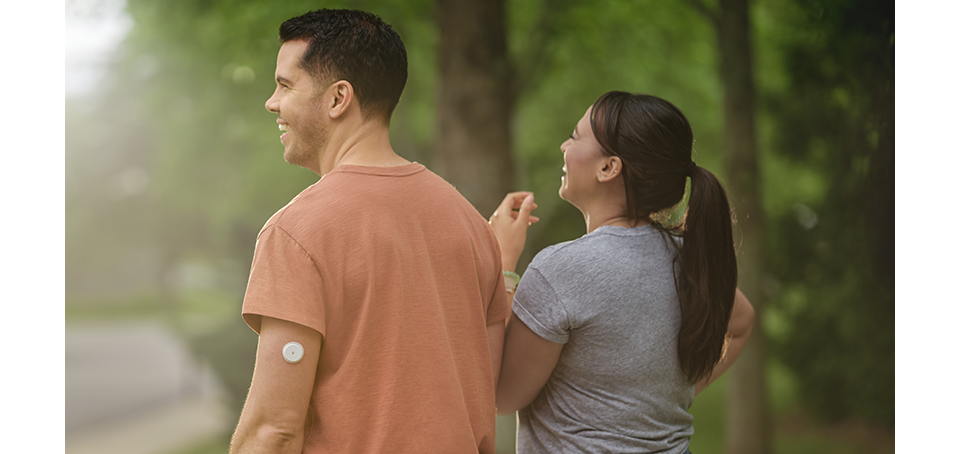 Couple walking in a park, the man is wearing a Libre 2 Plus sensor