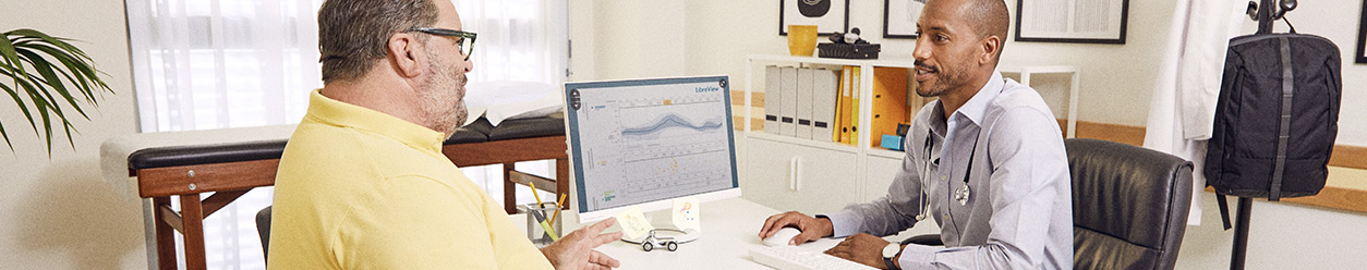 A health care professional showing a patient his Libreview report on screen