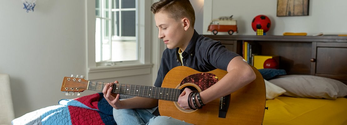 Teen playing guitar with FreeStyle Libre sensor on