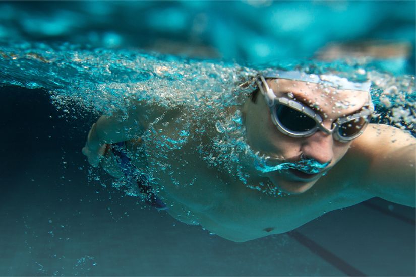 Homme en maillot de bain et lunette qui nage dans une piscine