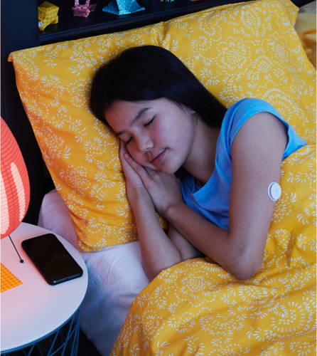A girl sleeping with FreeStyle Libre 2 sensor visible on the back of her upper arm