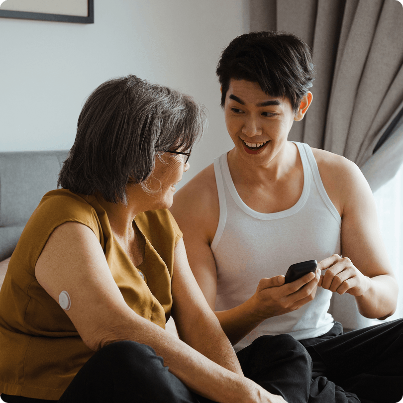 Caregiver and person wearing FSL sensor reviewing readings on smartphone or reader