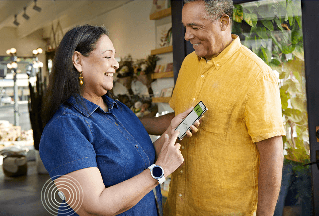 Man and woman with the FreeStyle Libre 2 sensor looking at their glucose levels on their phone 