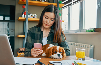 Girl sitting on desk holding a phone and her puppy