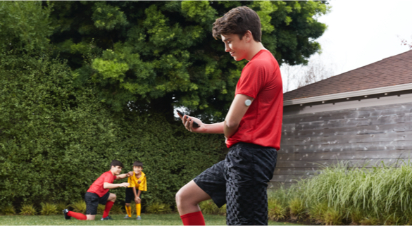 jongen in tuin kijkt op smartphone met freestyle libre 2 sensor op