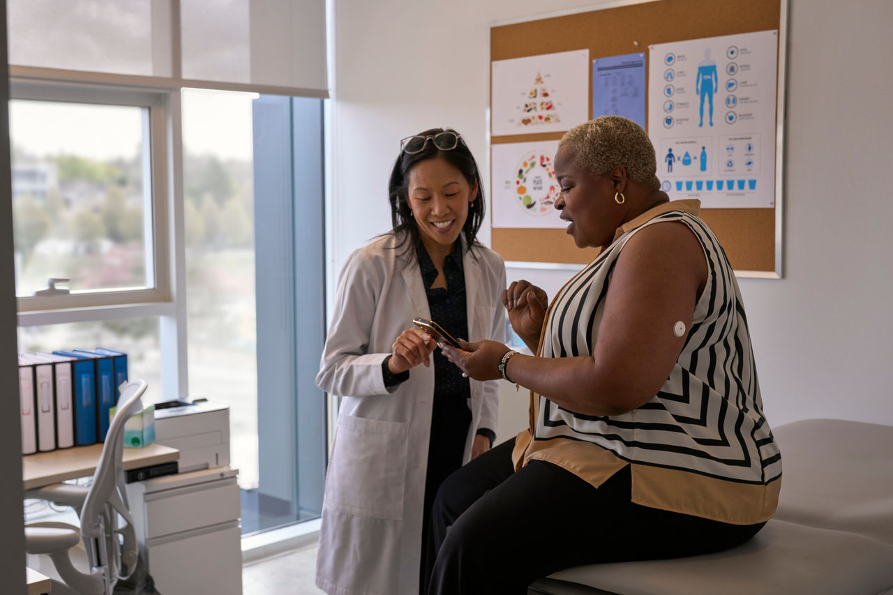 An HCP showing a FreeStyle Libre 2 Plus patient their glucose readings on a smartphone