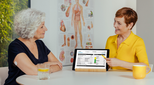 A FreeStyle Libre System user and Healthcare Professional sitting at the table talking about user's AGP Report. 
